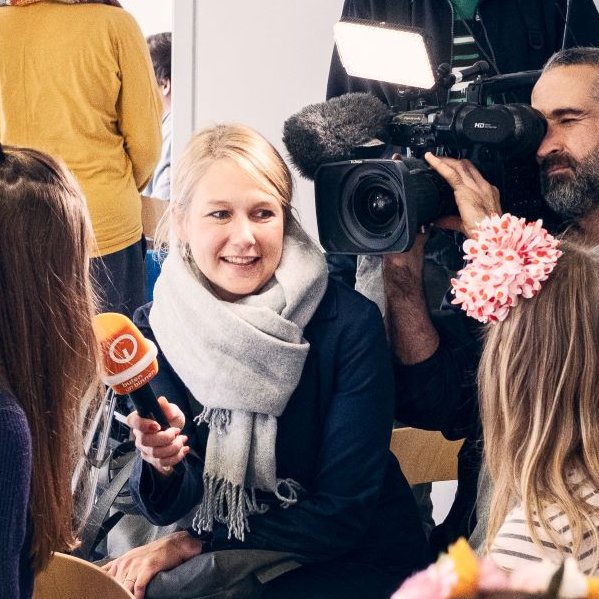 Ein Kamerateam interviewt Personen auf einer Veranstaltung.