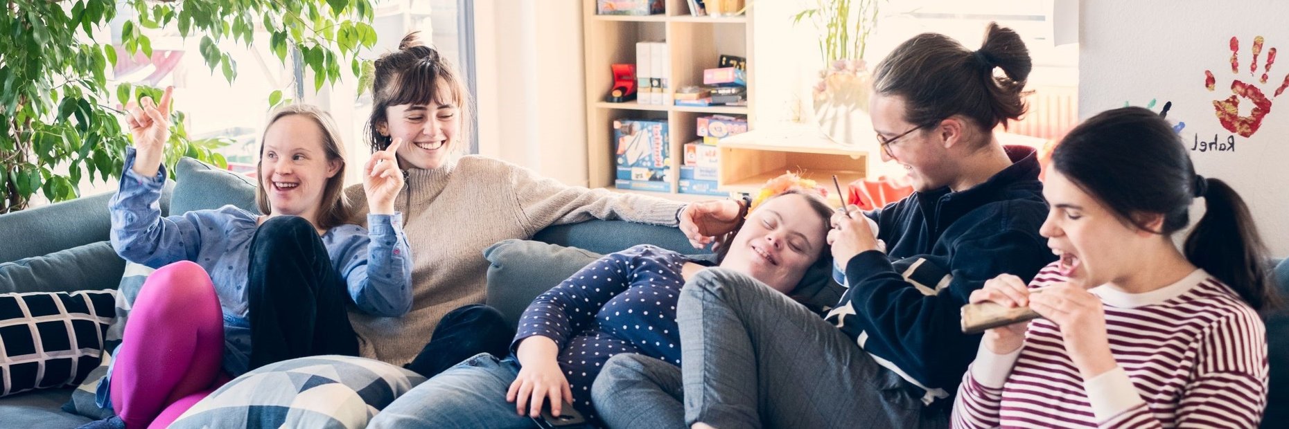 vier Bewohner einer inklusiven WG sitzen auf der Couch und haben gemeinsam Spaß