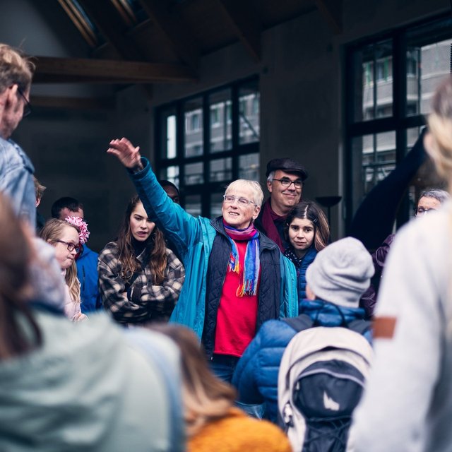 Eine Gruppe Menschen bei der Besichtigung des Blauhauses in Bremen. In der Mitte steht jemand und erklärt gestikulierend.